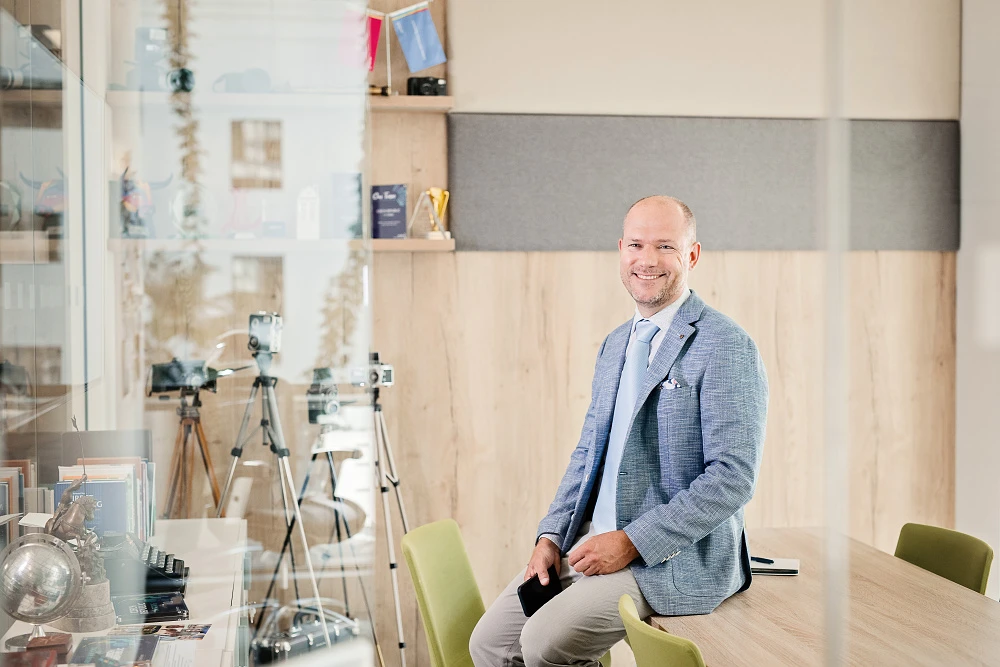 Profesionální byznys portrét muže v moderní kanceláři s přirozeným světlem, vhodné pro LinkedIn, webové stránky a osobní prezentaci, Praha.